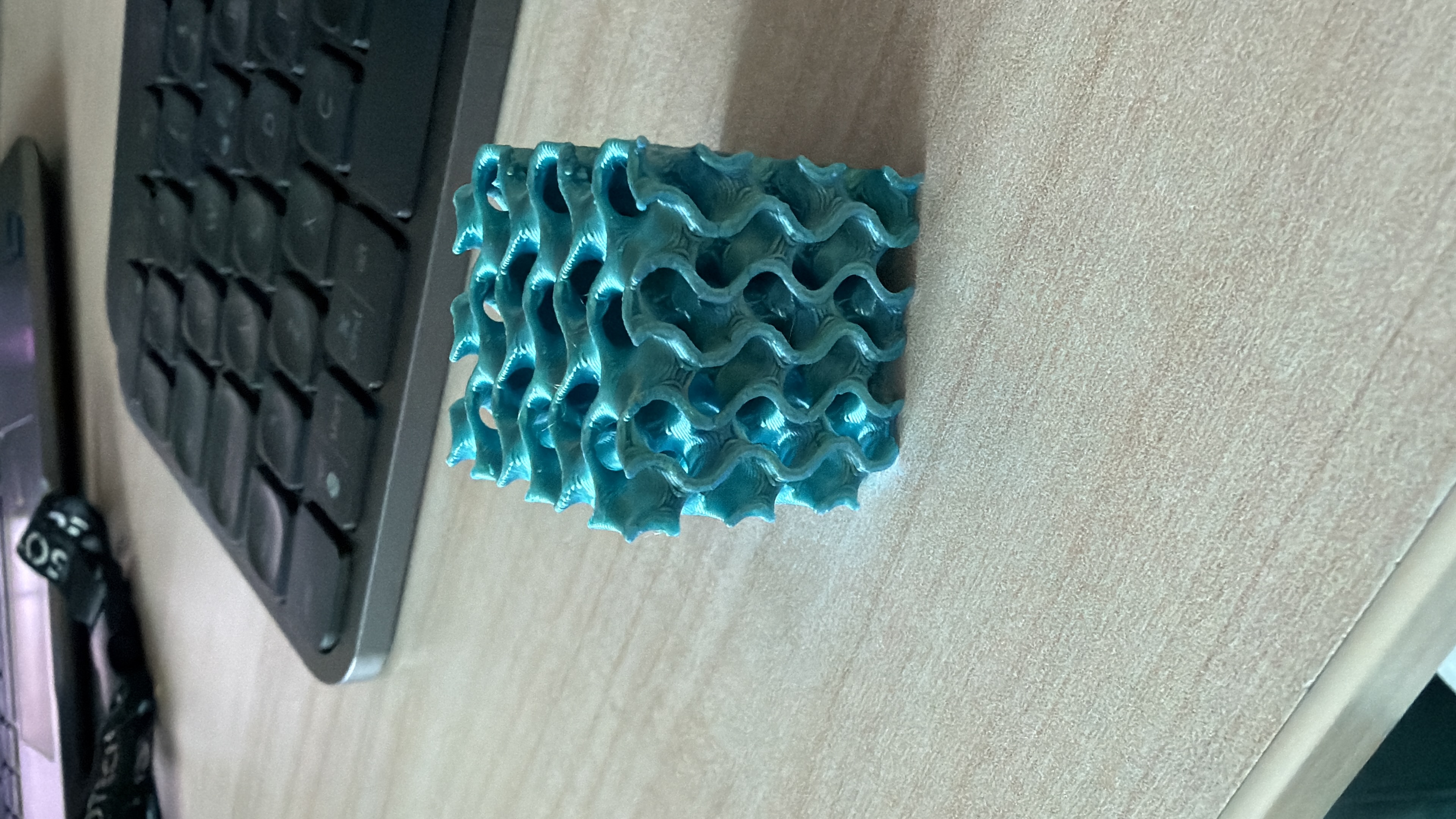 Close-up of the printed gyroid lattice cube showing its interconnected channel structure